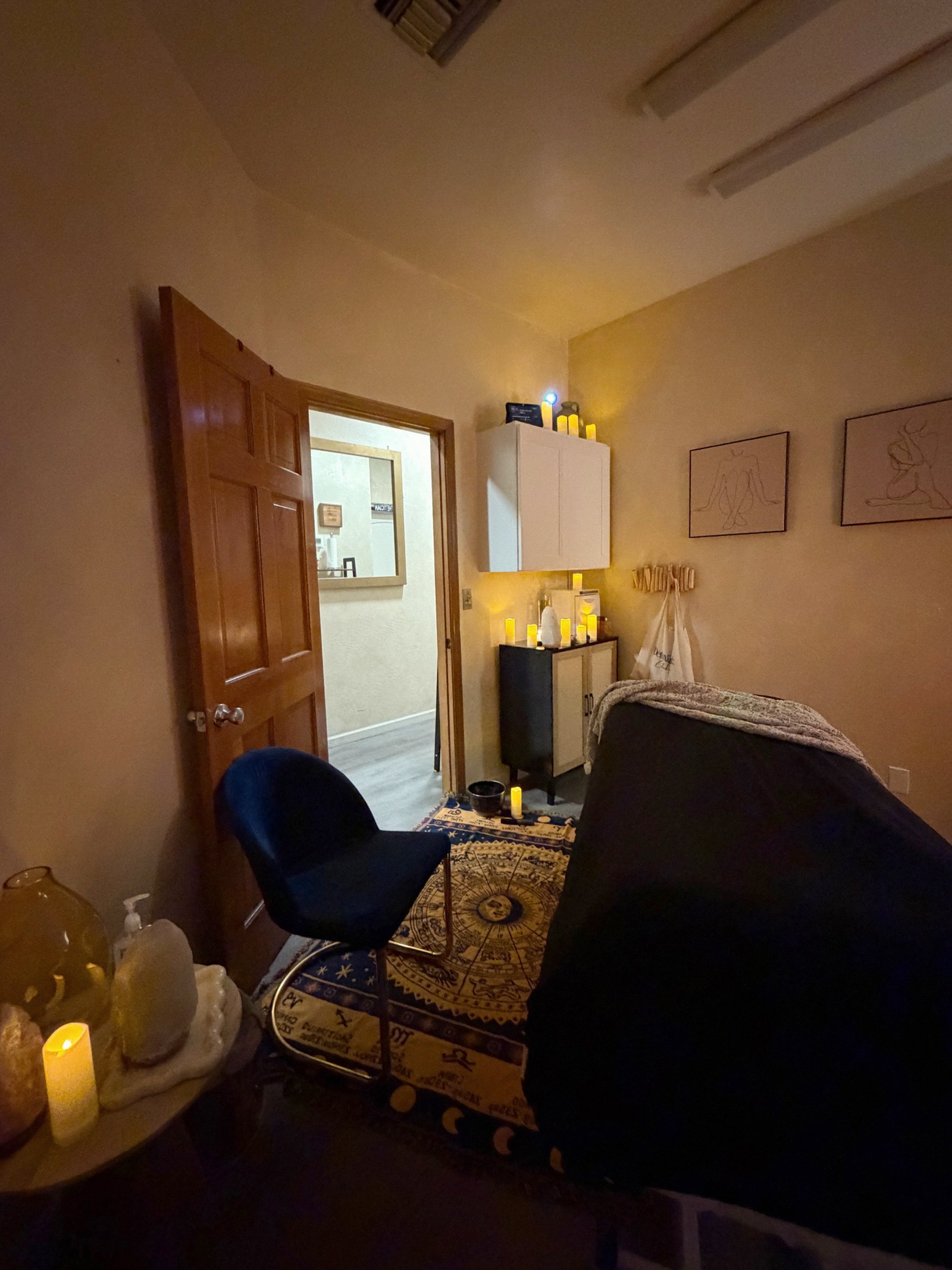 The candlelit treatment room where energy work sessions are held, with warm walls and low light